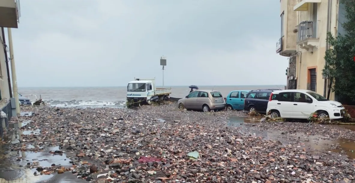 Colata di detriti e automobili sommerse lungo la costa etnea, simbolo degli effetti della cementificazione e della fragilità del territorio tra Etna e mare.