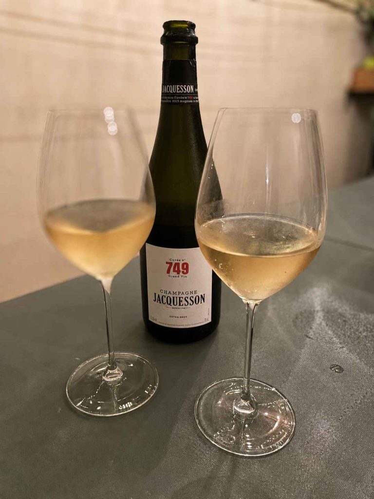 Bottiglia di Champagne Jacquesson Cuvée 749 Grand Vin, due calici colmi di champagne dorato