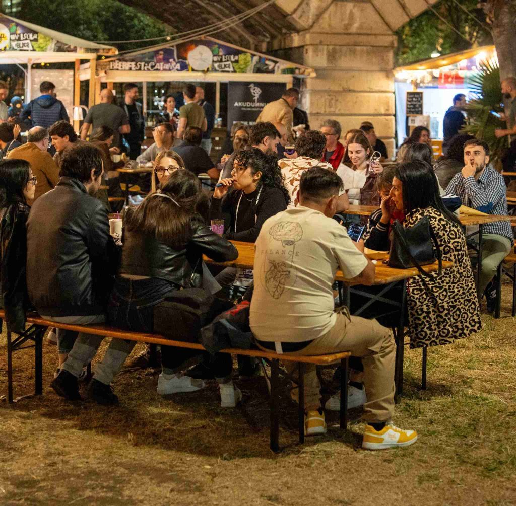 Persone sedute ai tavoli all'aperto durante un evento di degustazione enogastronomica